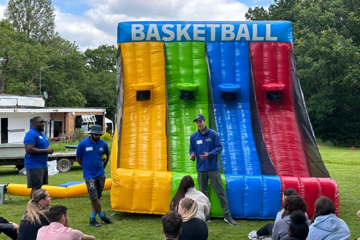 Inflatable basketball game setup outdoors with people gathered in front.