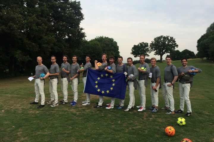 Group of people on grass holding EU flag and soccer balls.