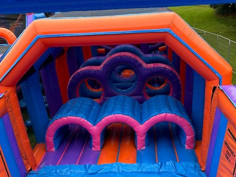 Colorful inflatable obstacle course with tunnels and arches on grass.