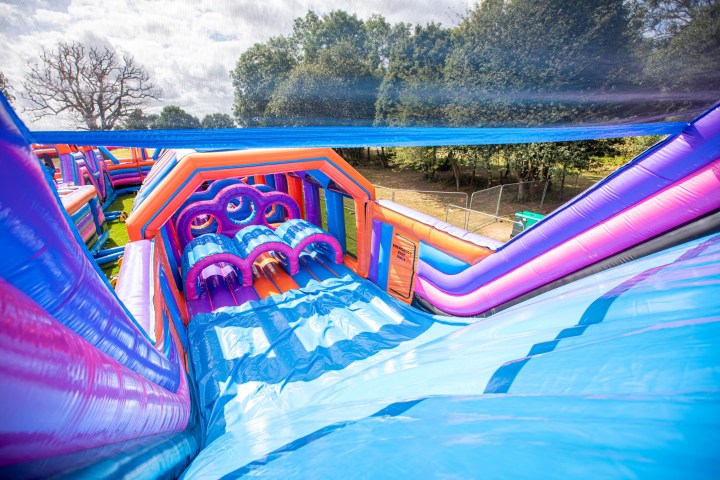 Colorful inflatable obstacle course with slides and arches in an outdoor setting.
