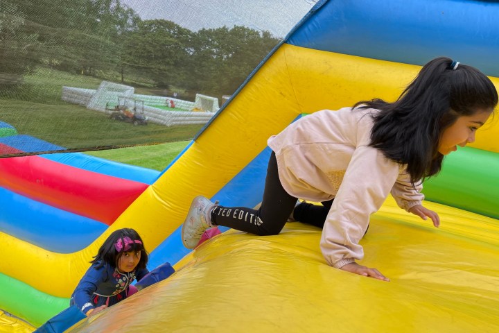 Two children climbing inside a colorful inflatable bounce house.