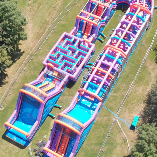 Aerial view of large, colorful inflatable obstacle courses on grass.