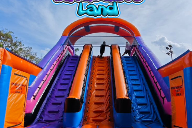 Colorful inflatable slide with people climbing, labeled 'Inflatable Land' at the top.