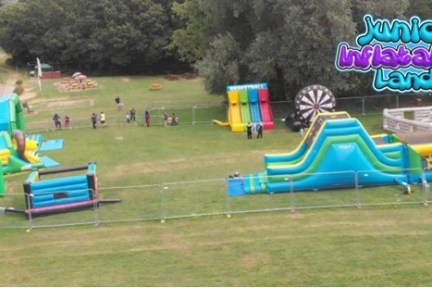 Aerial view of an inflatable playground with slides and obstacles on grass.
