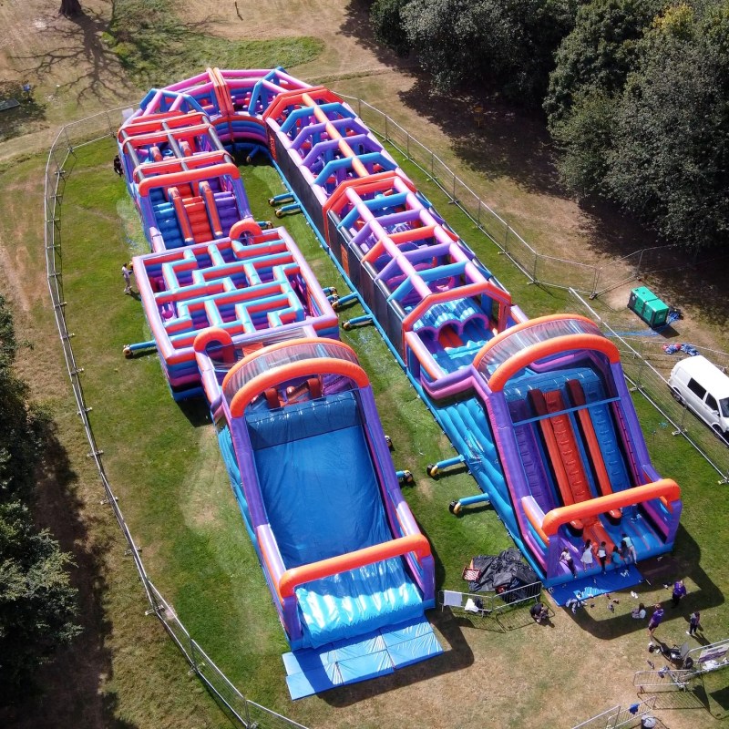 Inflatable obstacle course with slides and tunnels set up in a park.