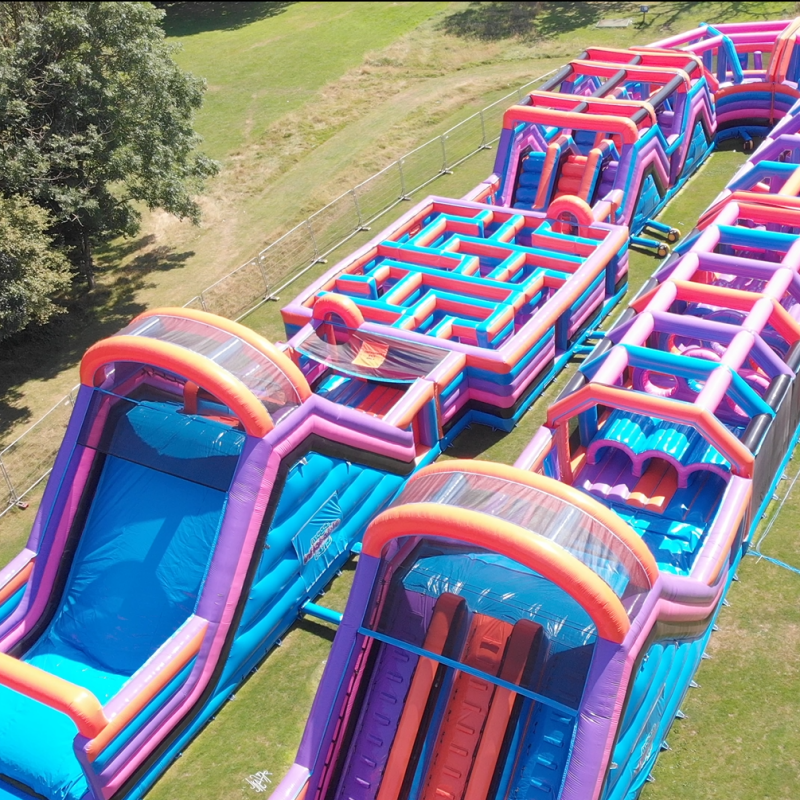 Aerial view of a colorful inflatable obstacle course on grass.