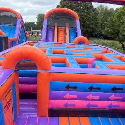 Colorful inflatable obstacle course with climbing slides and maze set outdoors.