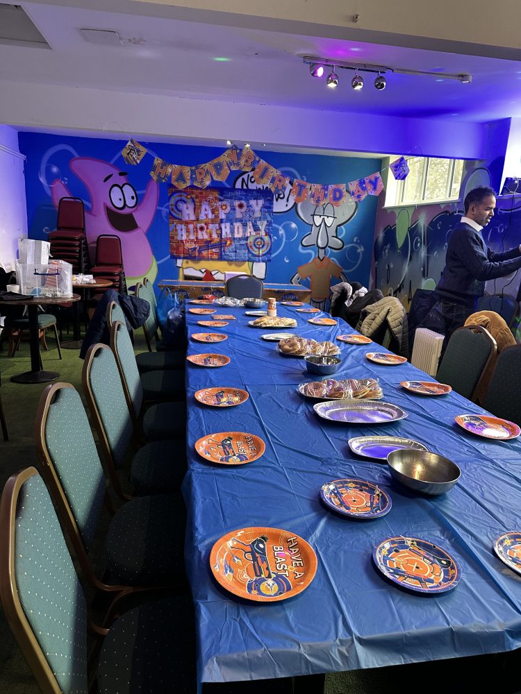 Party table with blue tablecloth, space-themed plates, and colorful wall decorations.