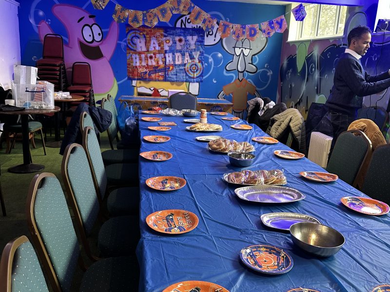 Party table with blue tablecloth, space-themed plates, and colorful wall decorations.
