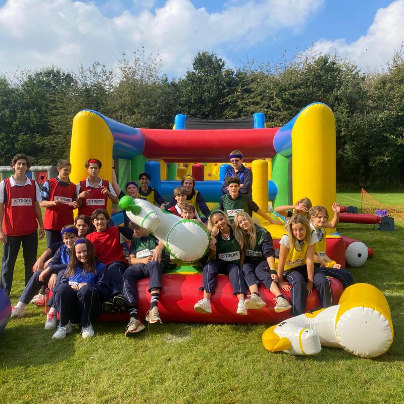 Group of people posing on inflatable obstacle course outdoors.