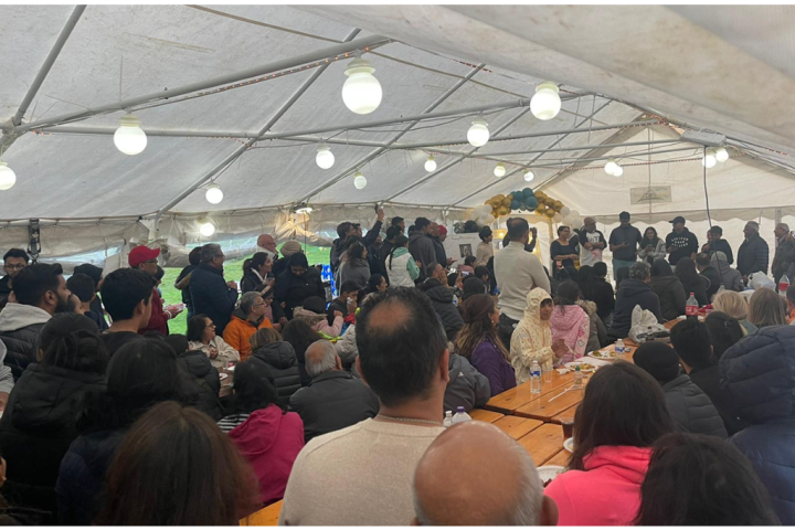 People gathered under a large white tent with hanging lights.
