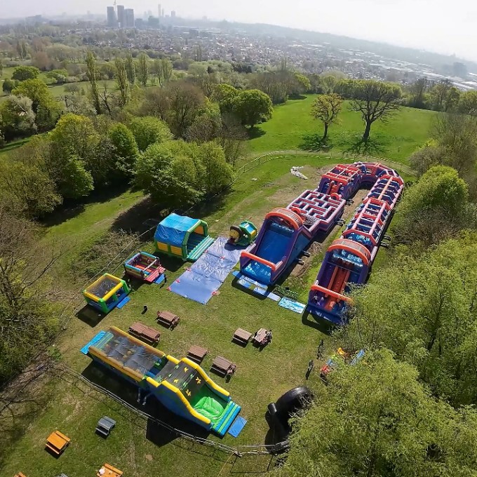 Aerial view of an inflatable obstacle course in a green park setting.