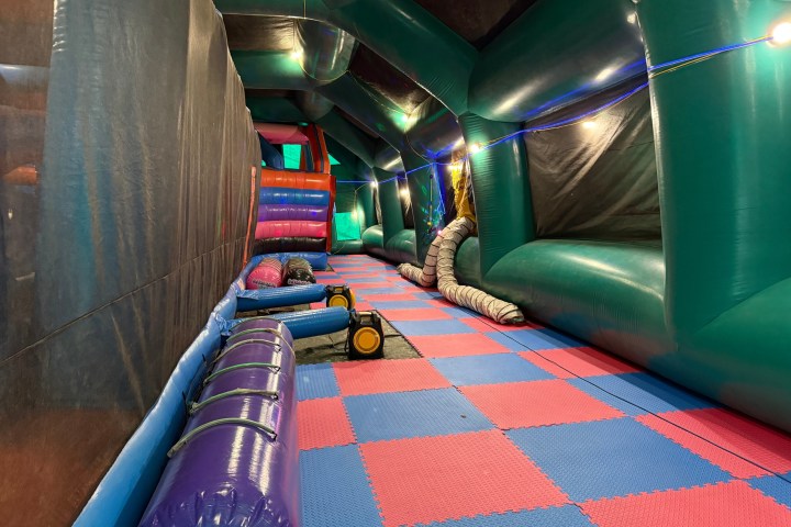 Inflatable obstacle course with colorful, padded floor and walls.