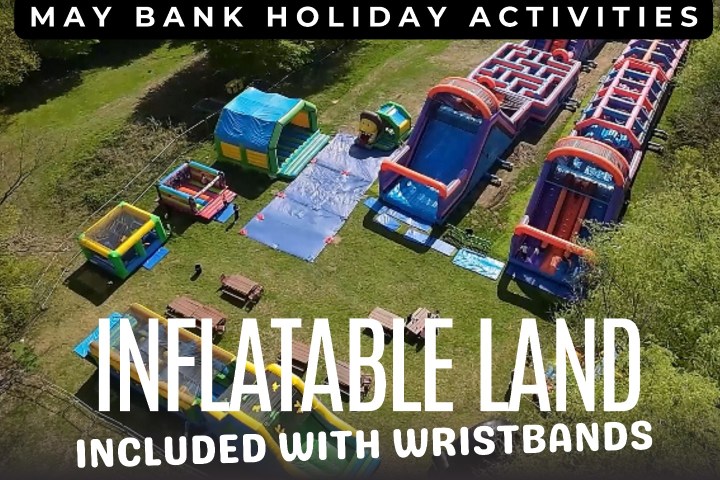 Aerial view of inflatable slides and bounce houses in a grassy park setting.