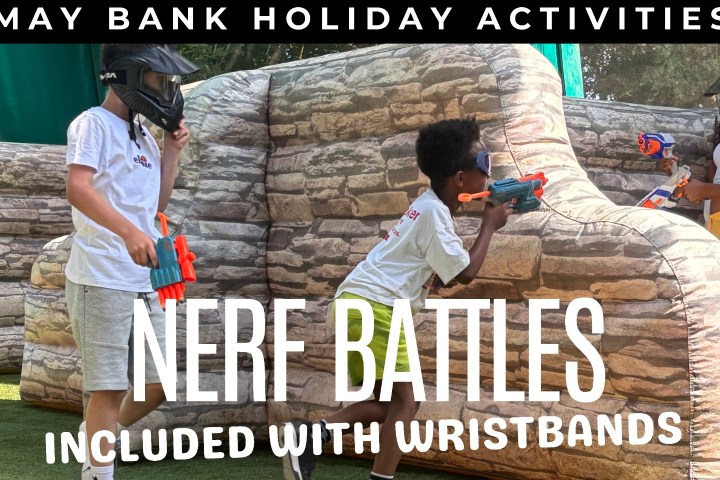 Children playing Nerf battles near inflatable barriers, wearing helmets.